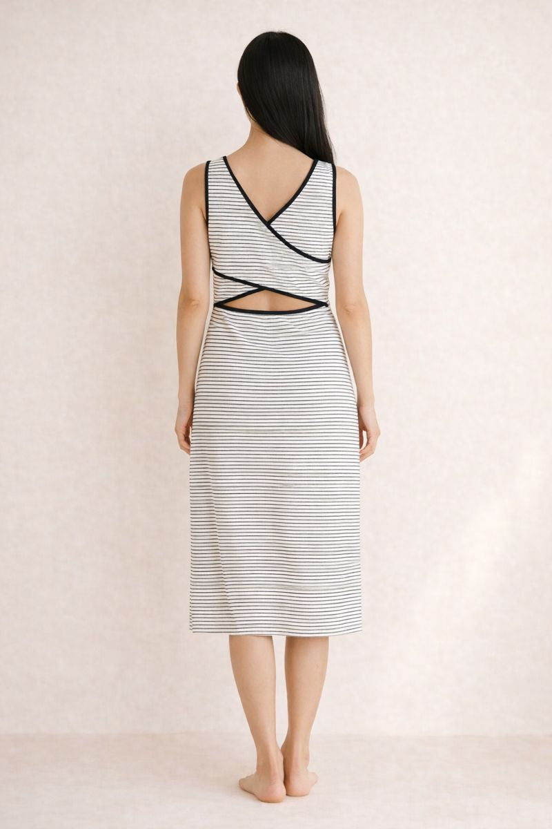 Woman wearing a black and white striped dress with cut-out design on a beige background