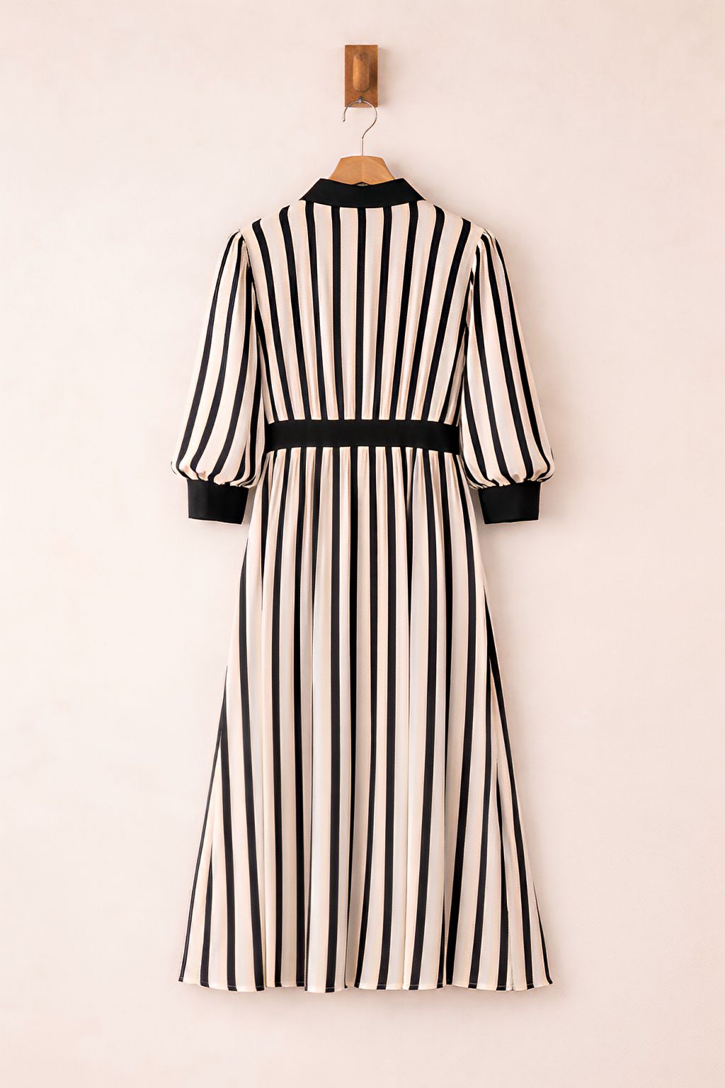Black and white striped dress on a hanger against a beige background