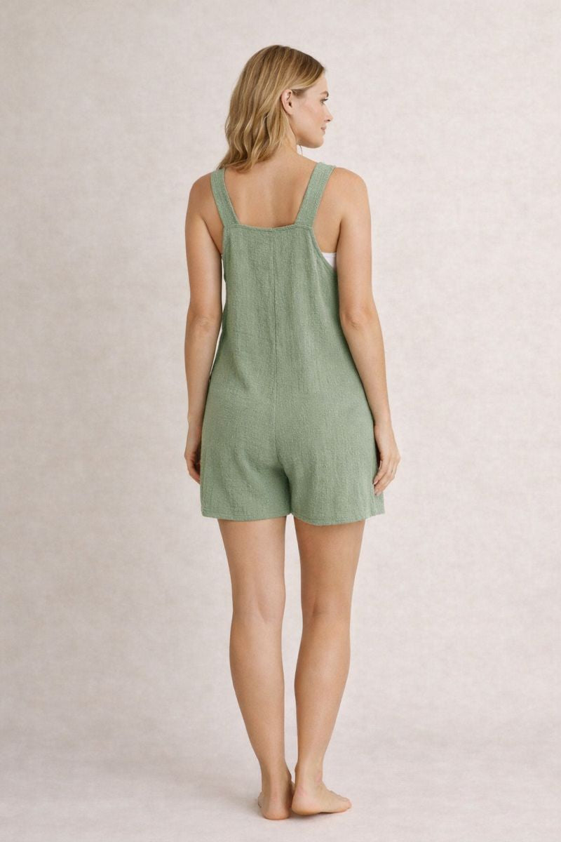 Woman wearing a green romper against a plain background