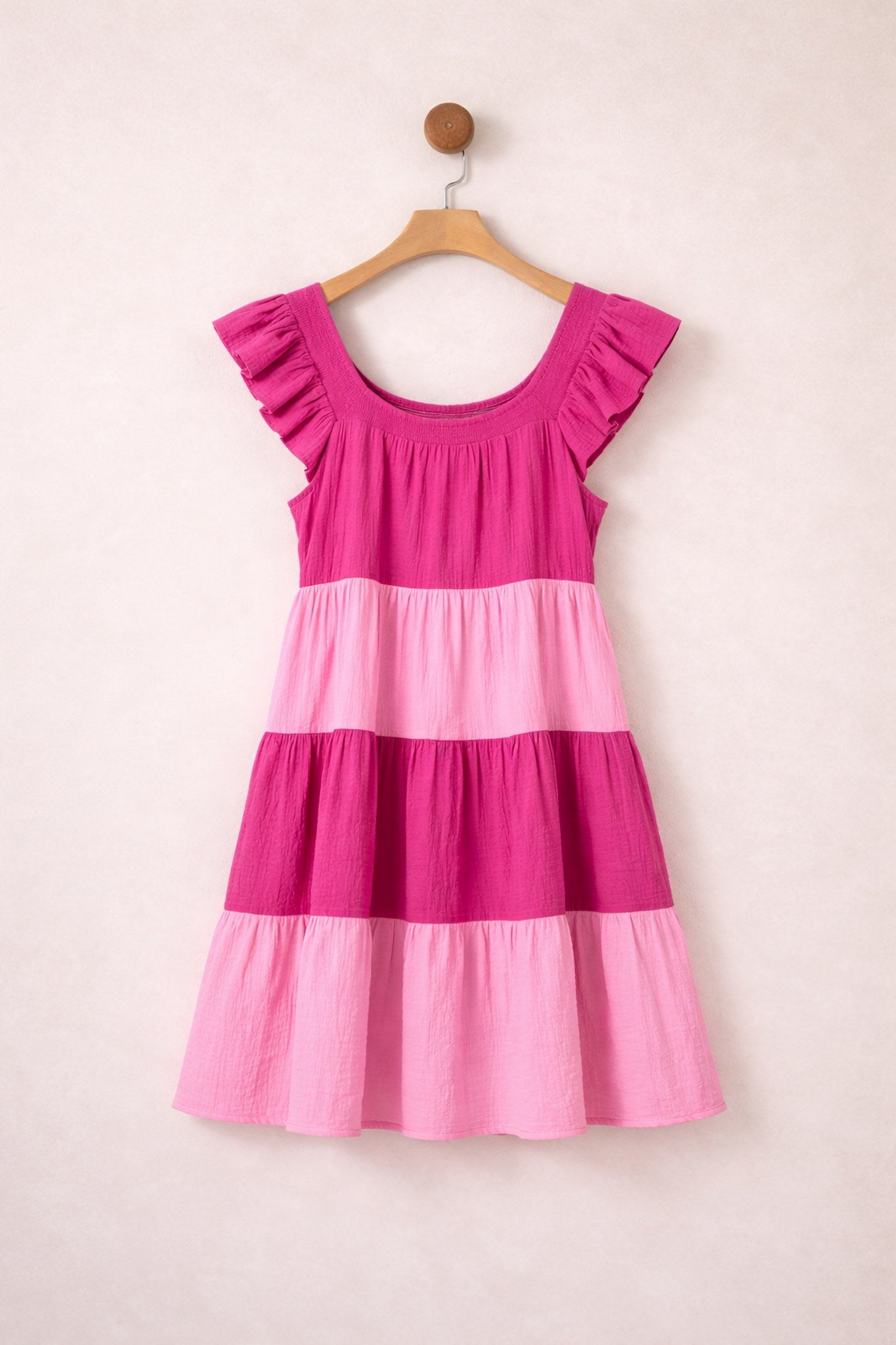 Pink and purple striped dress on a hanger against a light background
