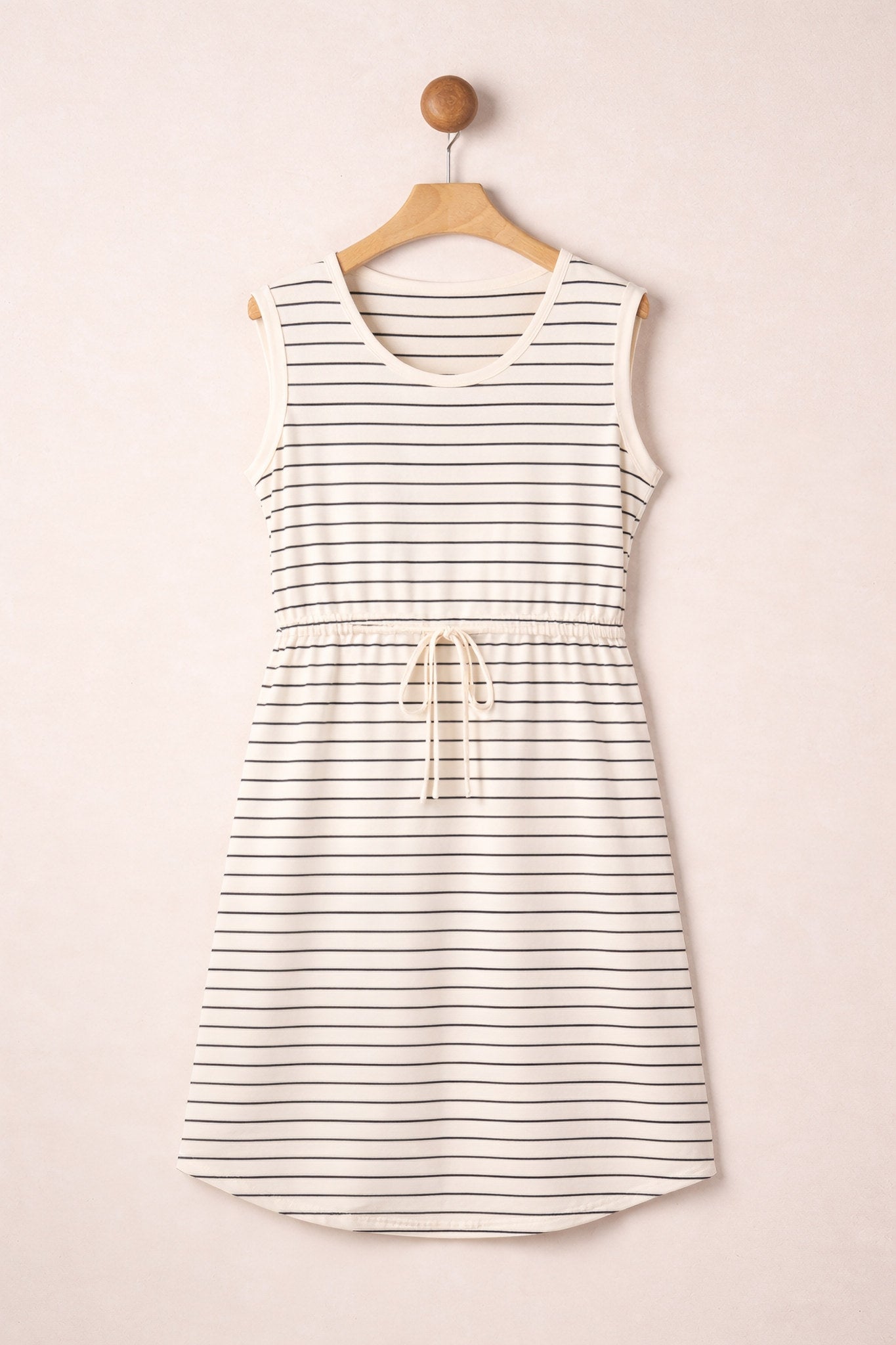 Striped dress hanging on a wooden hanger against a beige background