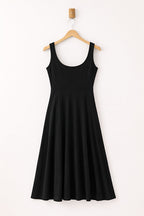 Black dress hanging on a wooden hanger against a white background