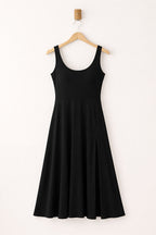 Black sleeveless dress on a hanger against a white background