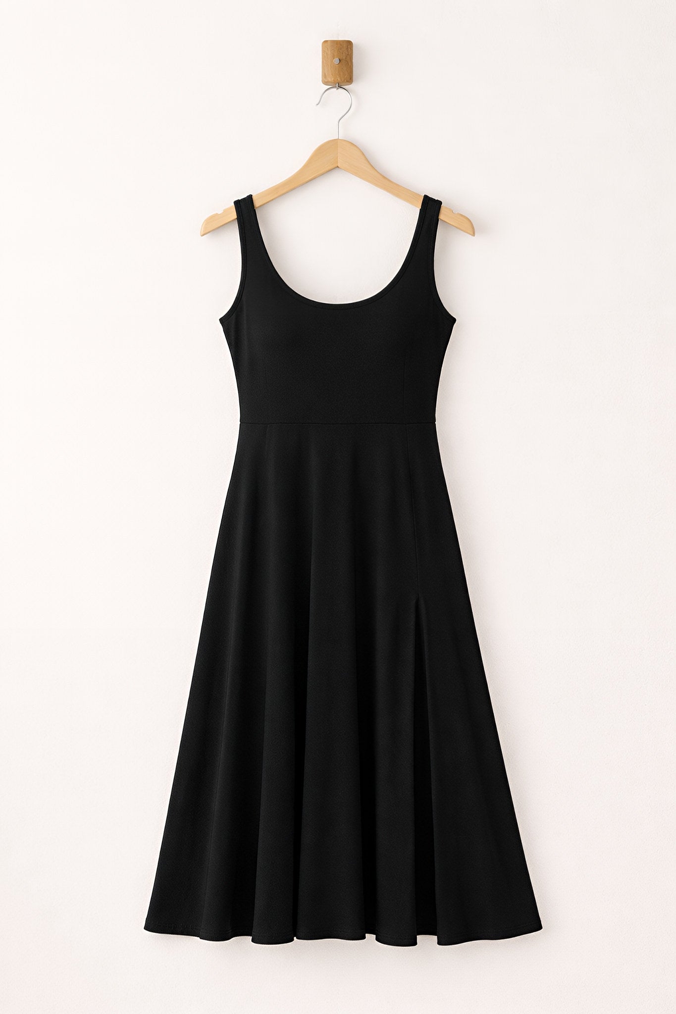 Black sleeveless dress on a hanger against a white background