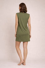 Woman wearing a green sleeveless dress against a plain background