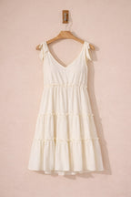 White dress on a wooden hanger against a pink background