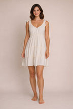 Woman wearing a white dress against a beige background