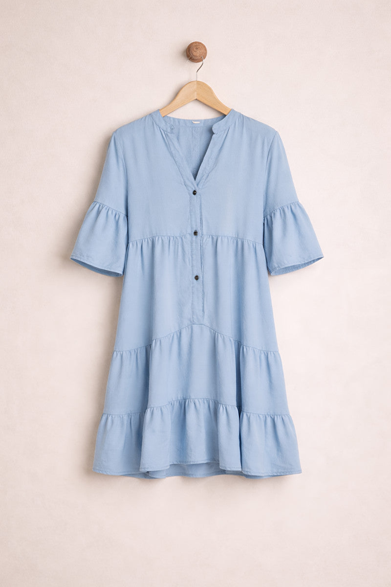 Light blue dress with ruffled sleeves and hem on a beige hanger against a beige background